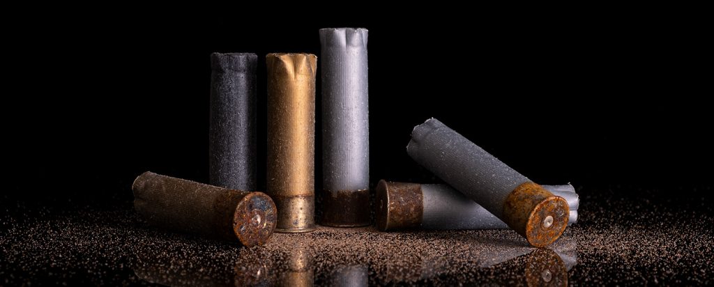 editorial product photography of Still life of gun shot shells on reflective black background